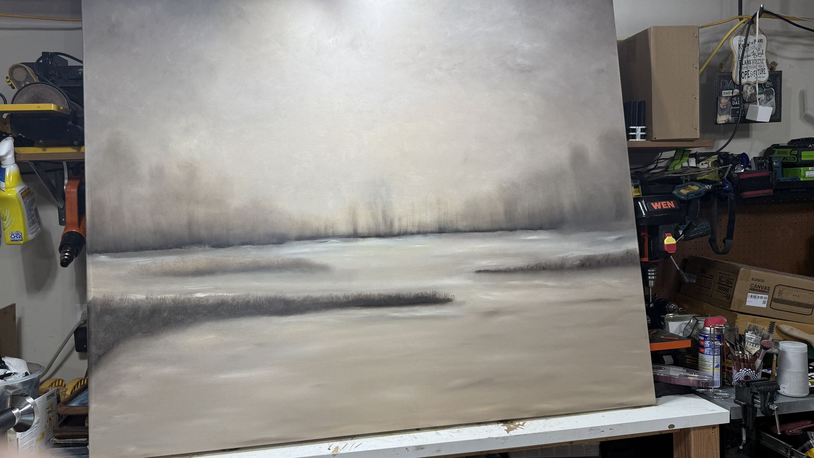 Jen's large misty marsh landscape in oil paint, propped on the workbench in her garage studio